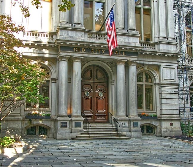 A historic city hall building with antique wooden doors requires detailed architectural restoration and maintenance services