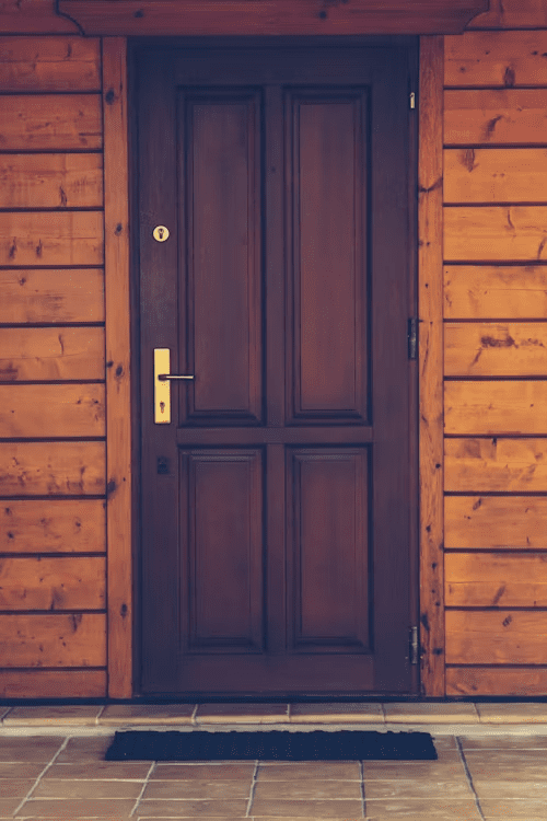 Exterior of home with hand-crafted wooden door to represent innovative techniques in architectural finishing for exterior woodwork